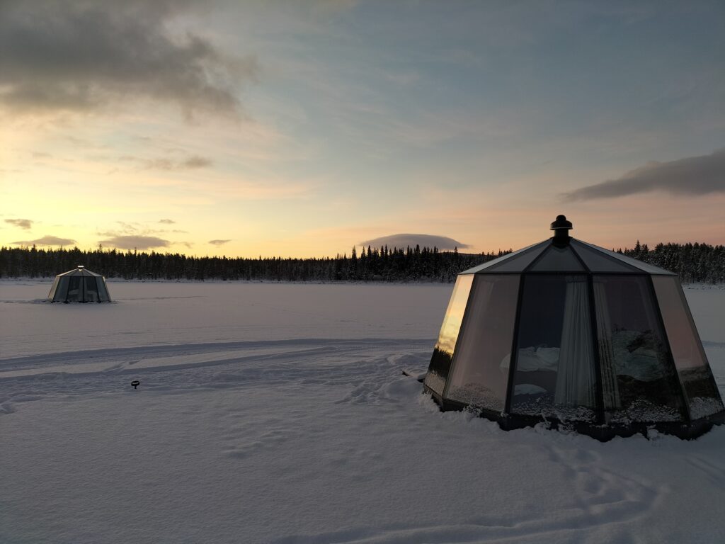 Two glass igloos on the frozen river in Kurravaara.