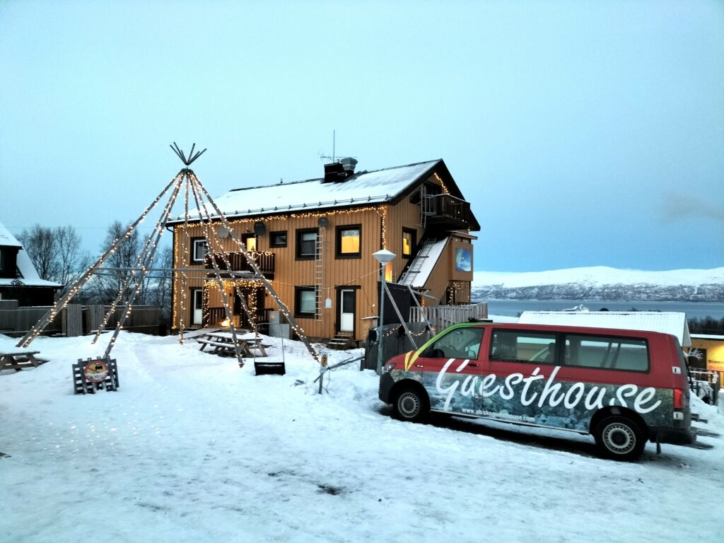 View from outside of the Abisko Guesthouse & Activities. Minivan in the foreground and the guesthouse on the background.