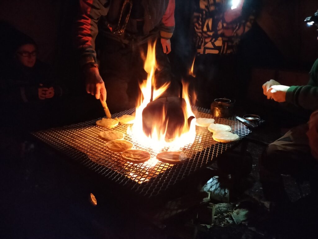 Eating bread outside around the campfire.