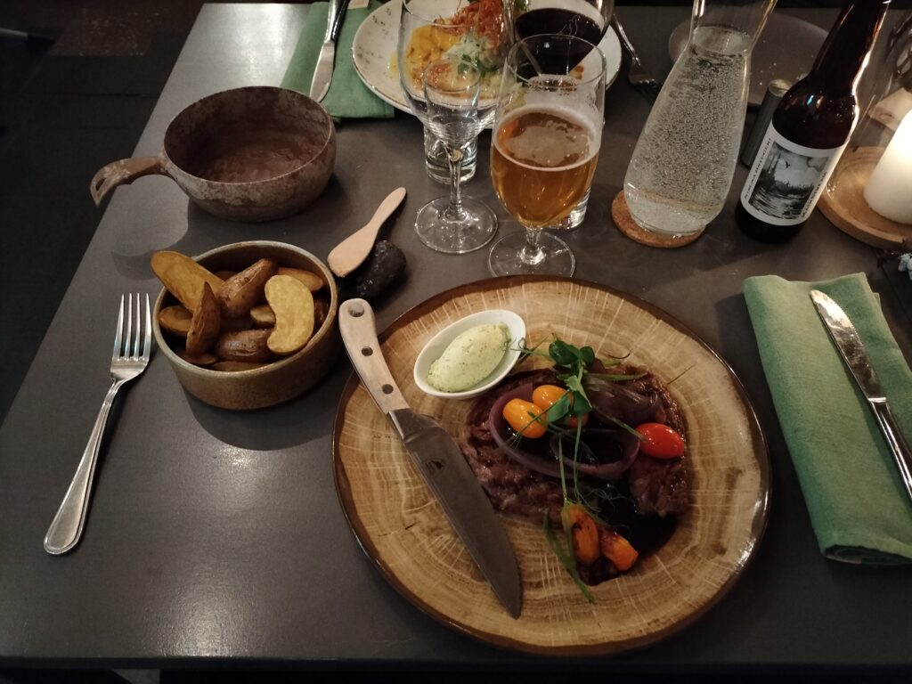 Main dish at Camp Ripan restaurant. There is a steak with roasted potatoes and a beer.