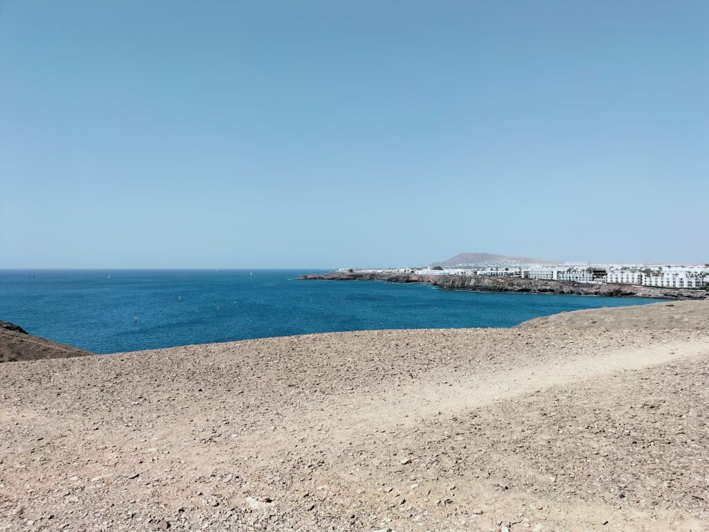 Beach with crystal blue sea and white houses in the background.