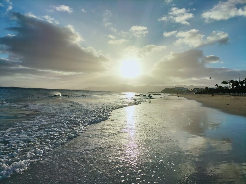 Playa Blanca beach with sand sea and sunset on the horizon. A person in the background.