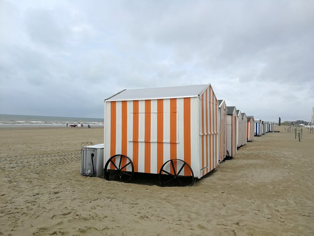 White and orange colored cabin with wheels on De Panne beach.