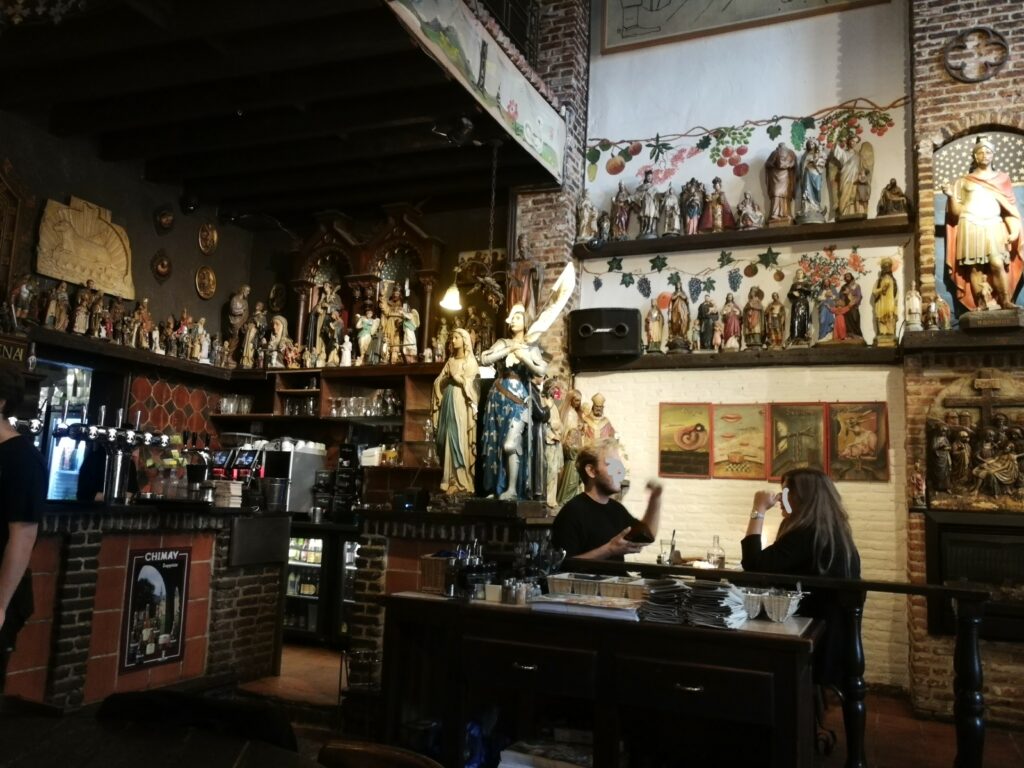 Inside the Elfde Gebod, a lot of religious statues on the walls and two persons talking.