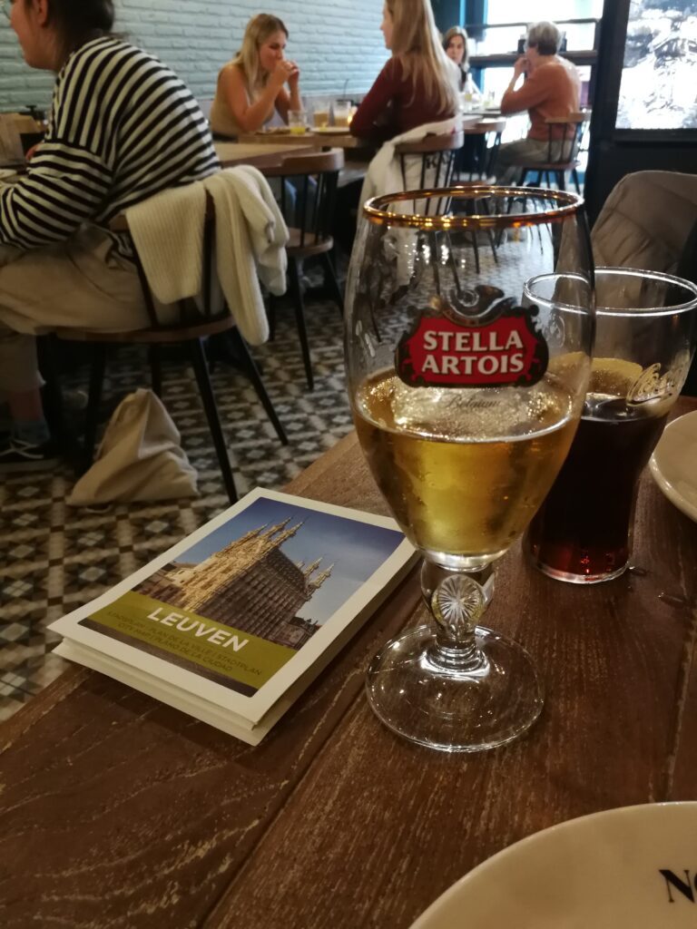 A pint of beer Stella Artois on a table with the Leuven map. Other guest sit in the restaurant.