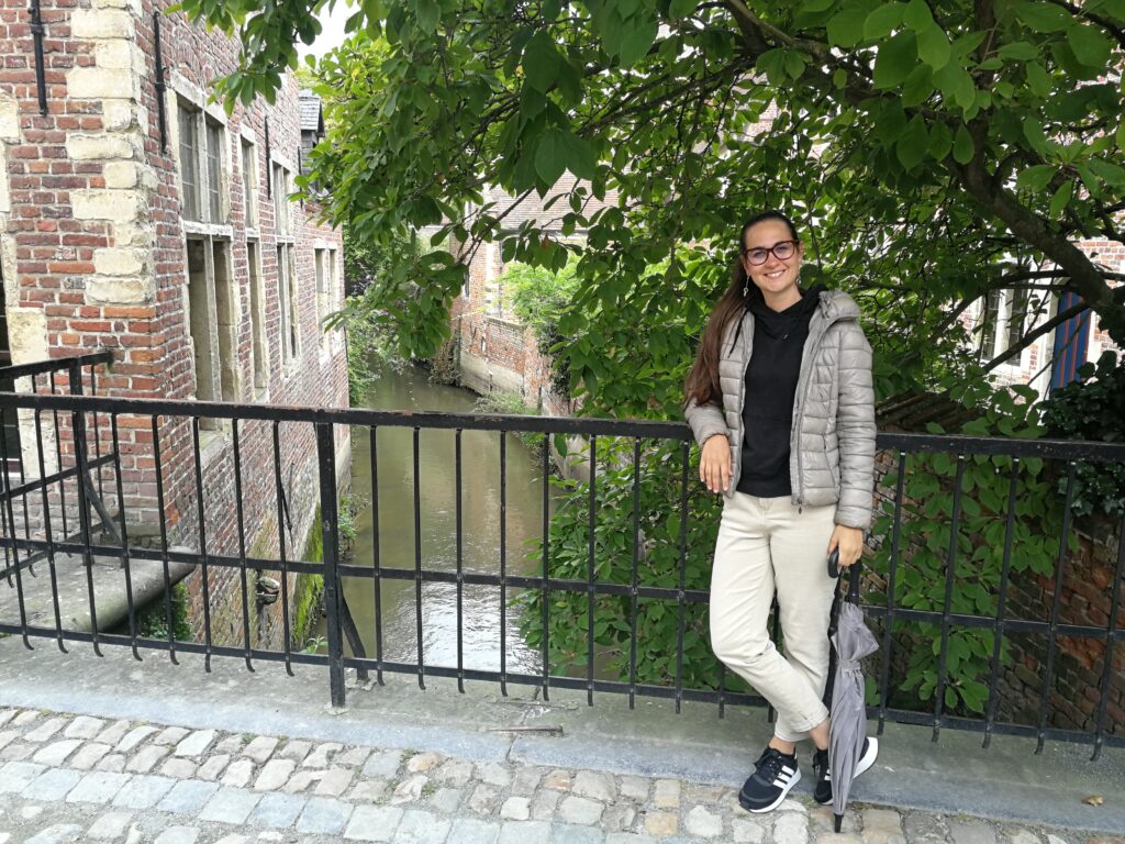 Claudia in the Great Beguinage neighborhood leaning on a railing. Behind the river.