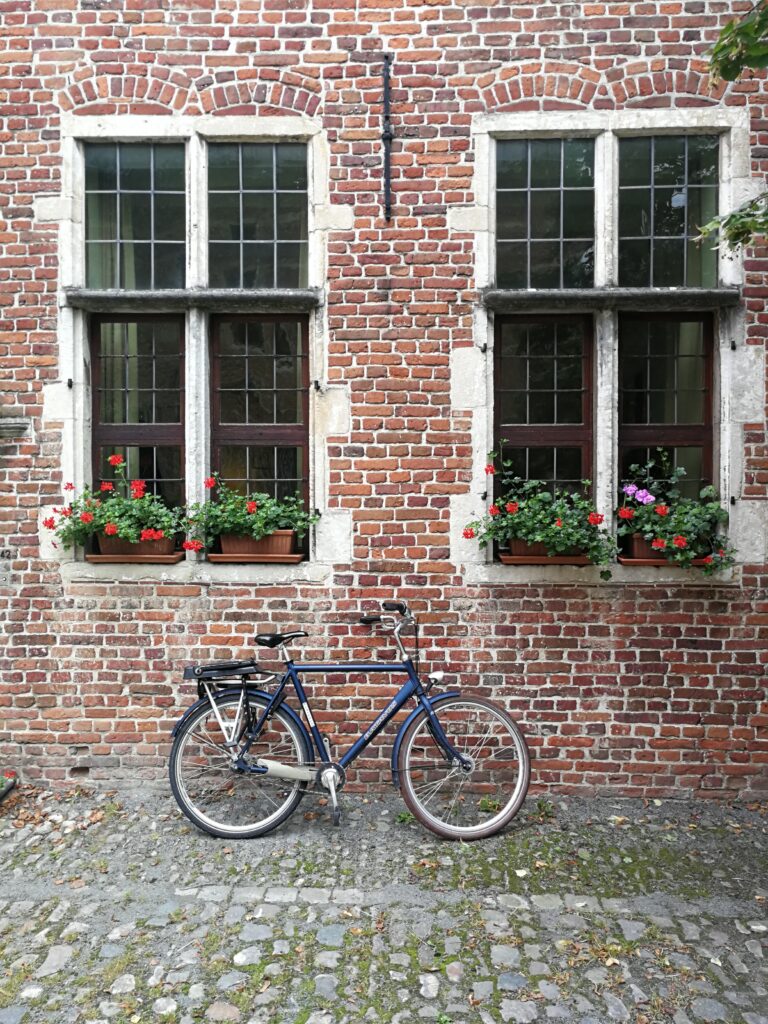 A bycicle in the Great Beguinage neighborhood leaning on a wall of red bricks.