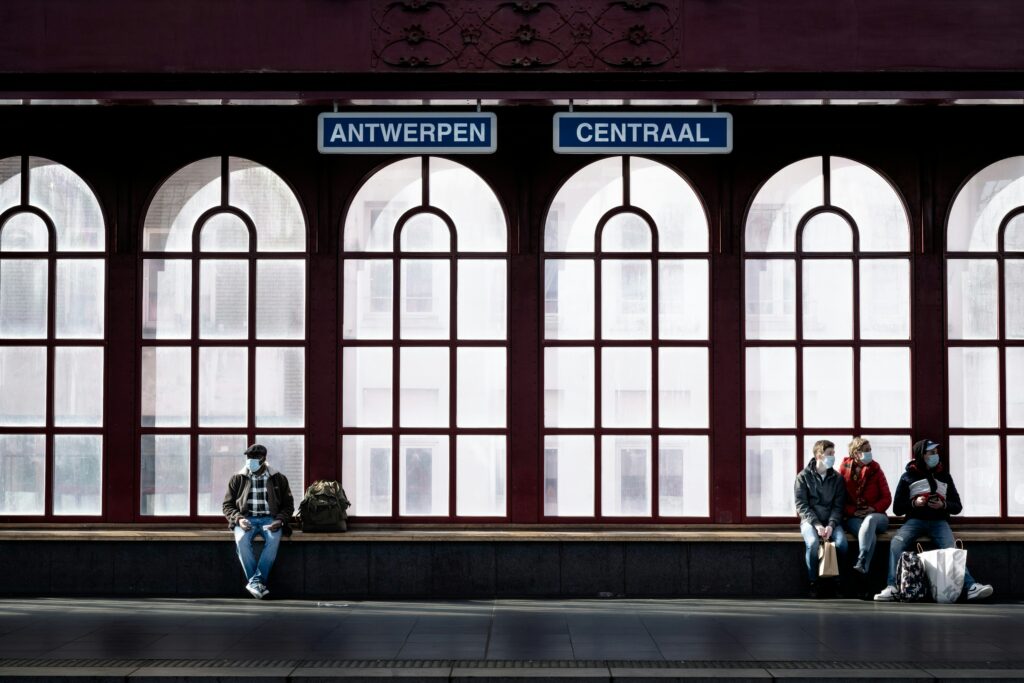 Central station in Antwerp. 4 people are sit on the bench waiting for the train.