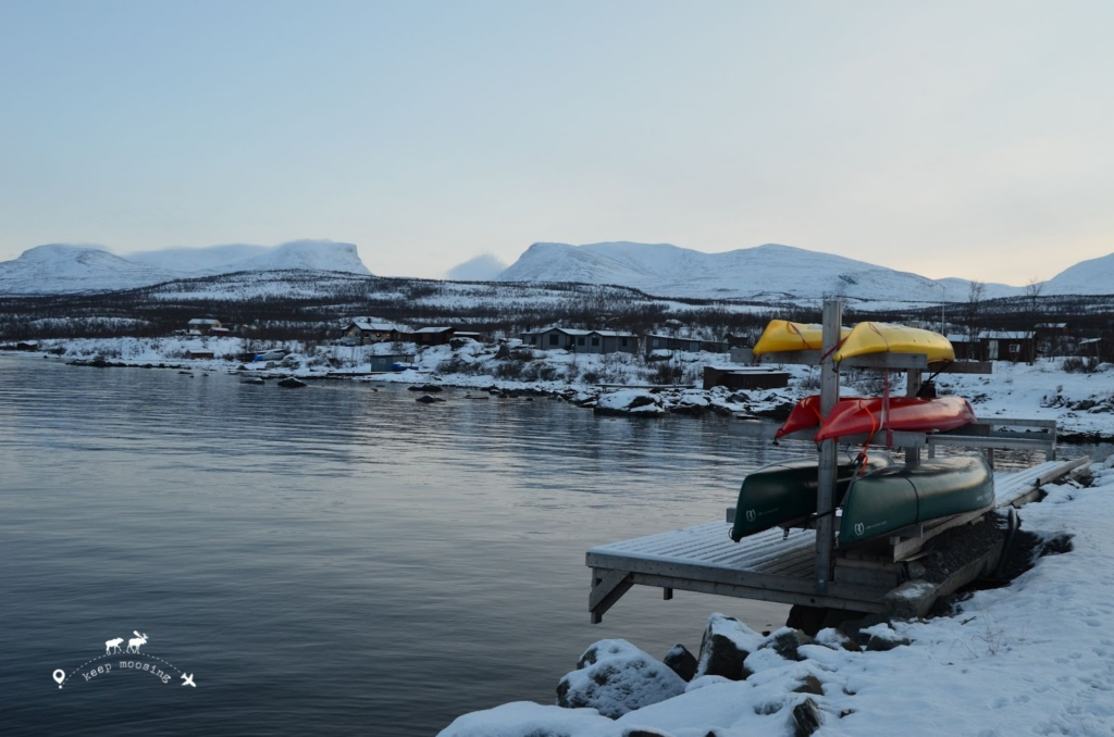 Tornetrask lake with three colorful canoes. In the background the snow-capped mountains around Abisko.