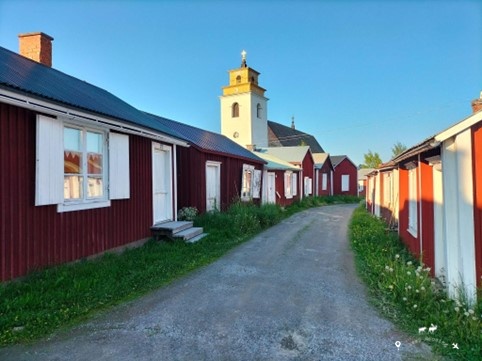 The main street of the UNESCO town of GAmmelstad with the typical wooden houses colored red and white on the sides. In the background the town's bell tower and the blue sky.