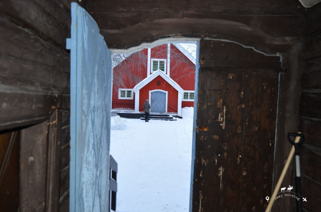 Claudia in front of a typical Lappish red church. The image is seen through the wooden door leading to the church complex.