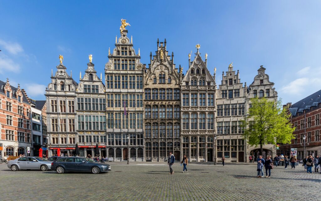 Picture of Grote Markt with a tree on the right and 2 cars on the left.