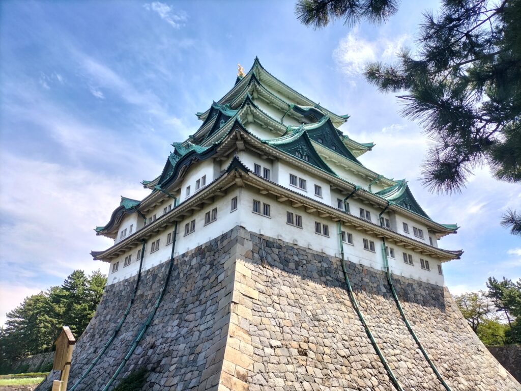 Nagoya Castle from the outside, on the right a tree branch and the blue sky in the background.