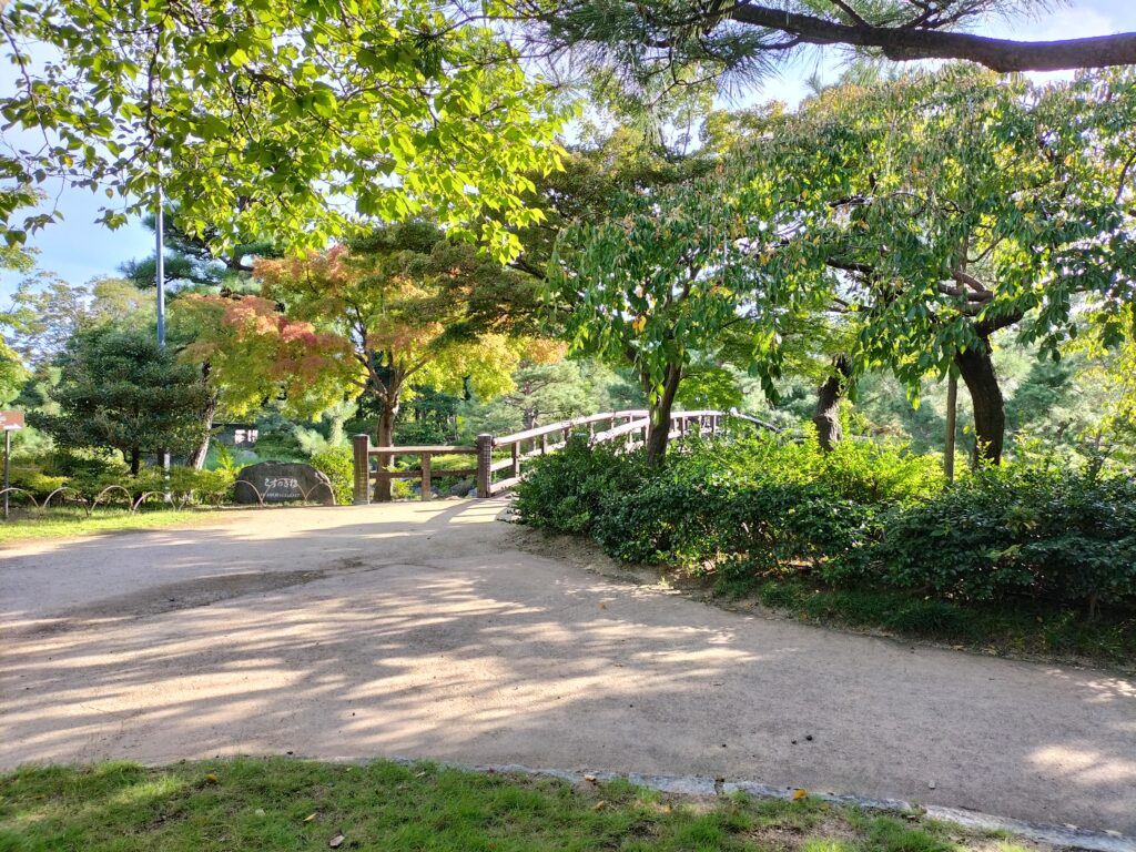 The bridge inside the Shirotori Garden with trees and lake in the background.