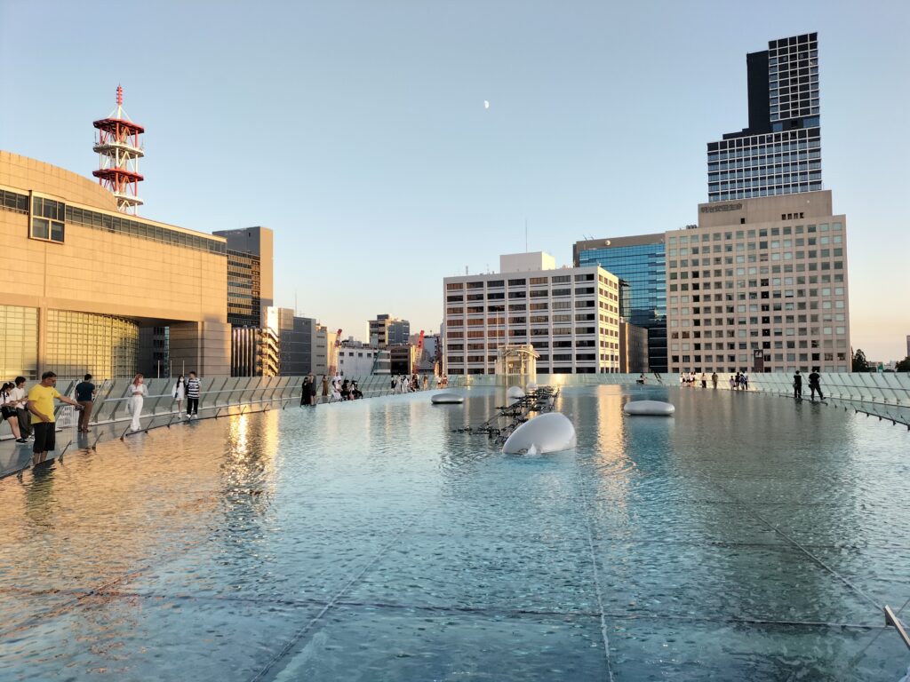 The roof of Oasis 21 with the water and the reflection of the surrounding buildings.