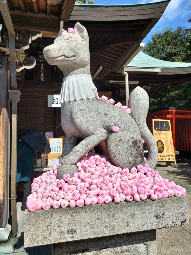 A statue of a cat with some small traditional Japanese objects.