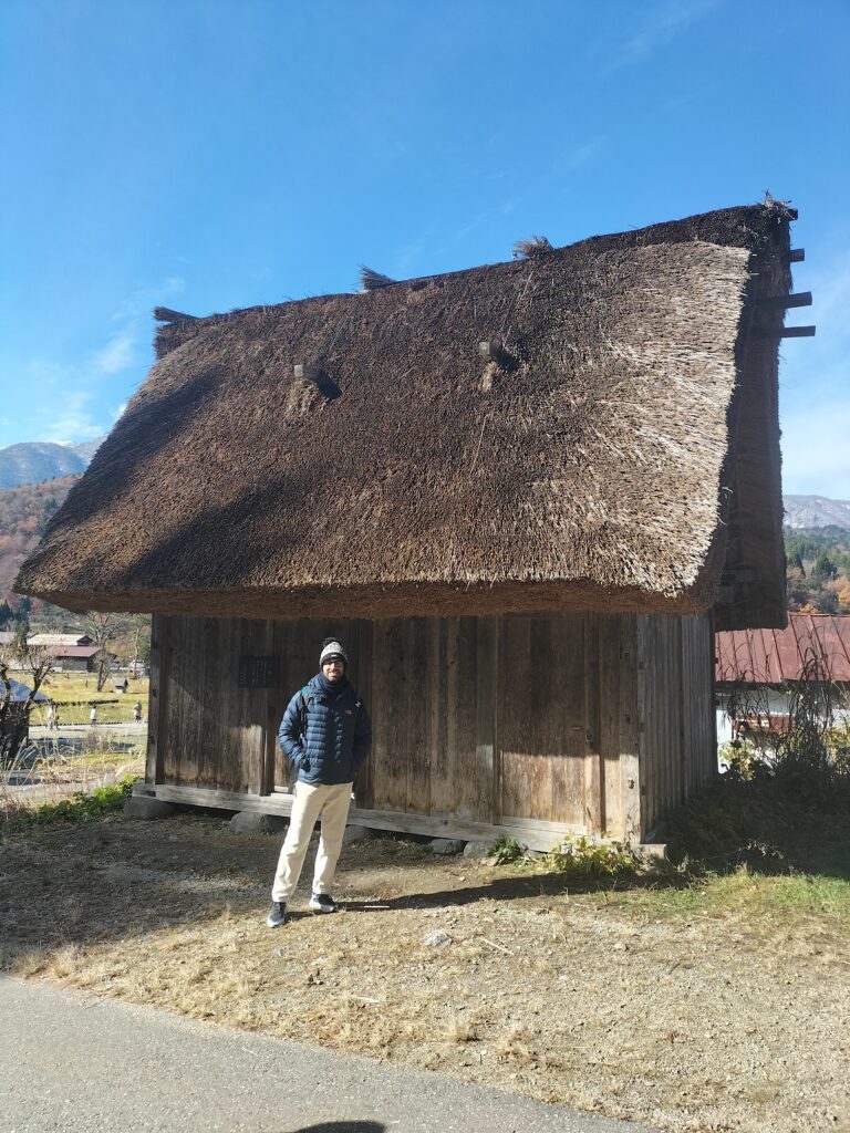 Tiziano in front of a typical house with a sloping thatched roof.