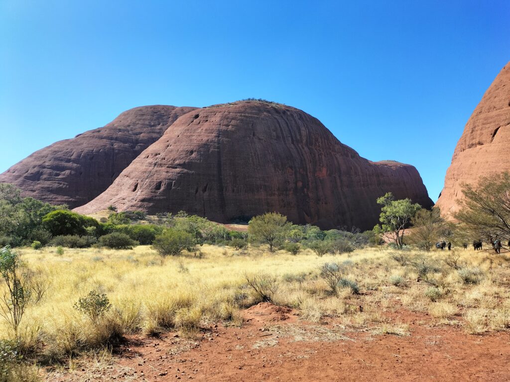 View of the Olgas with red sand and blue sky.