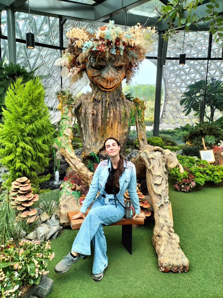 Claudia sit on a bench inside the Flower Dome.