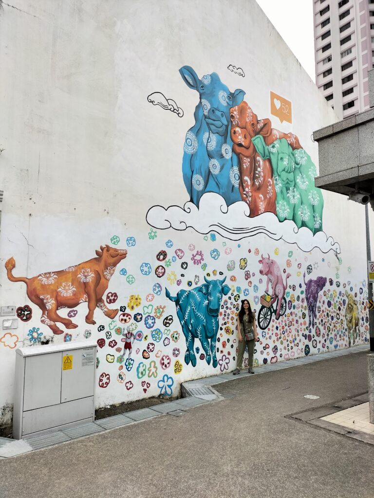 Image of Claudia with walls full of colorful cows behind her in little India.