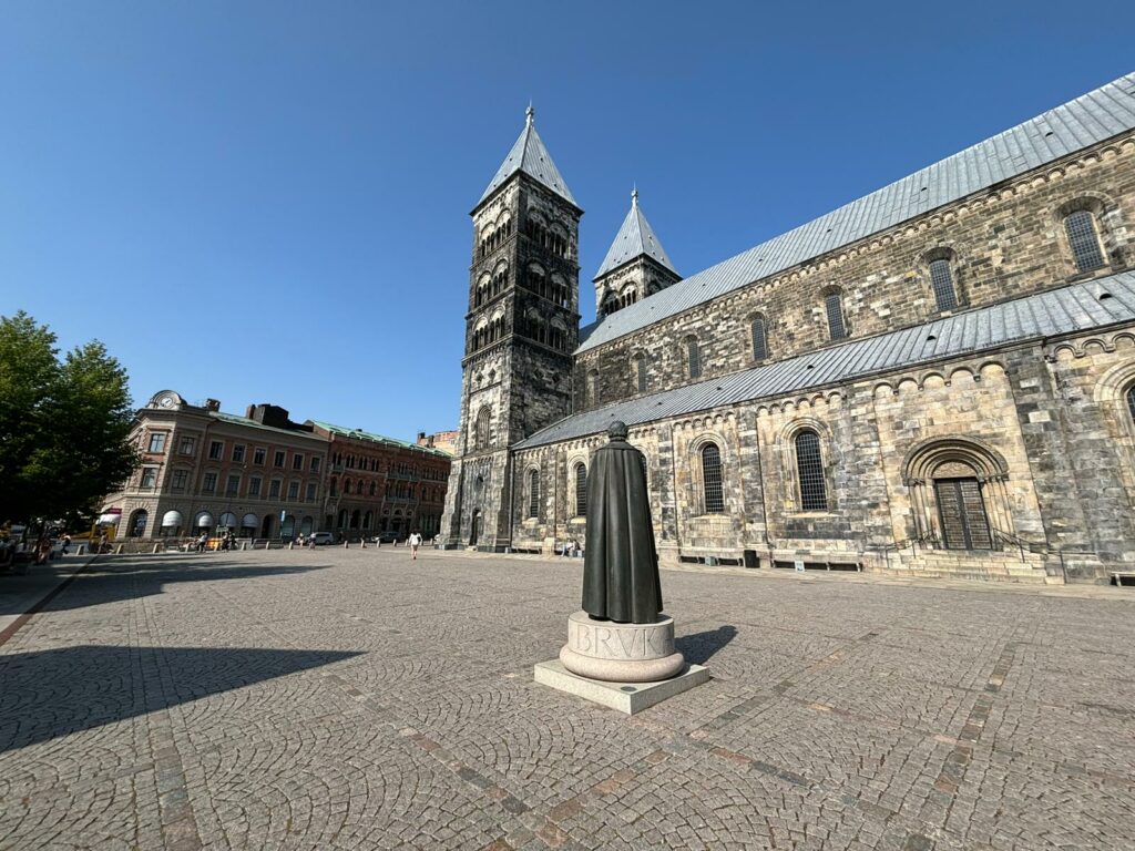 View of the cathedral of Lund. In the foreground there is a statue of a priest. what to do in Lund in 1 day