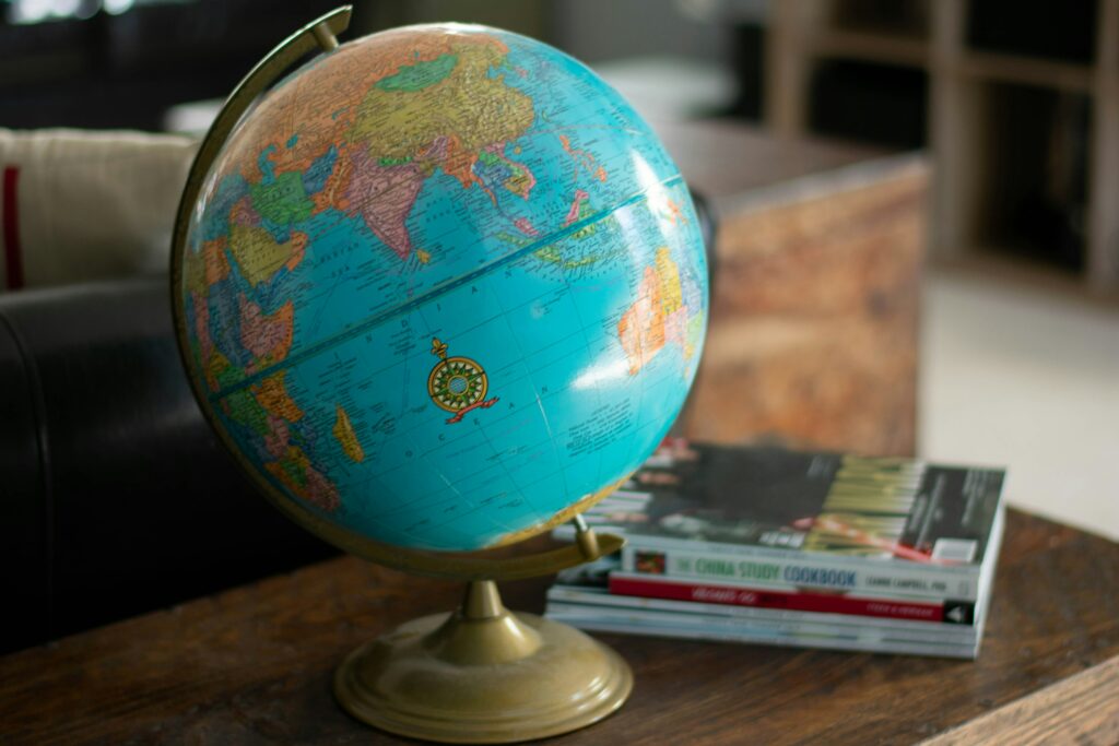 Image of a globe and some books on a table. Top 8 books to read if you love traveling