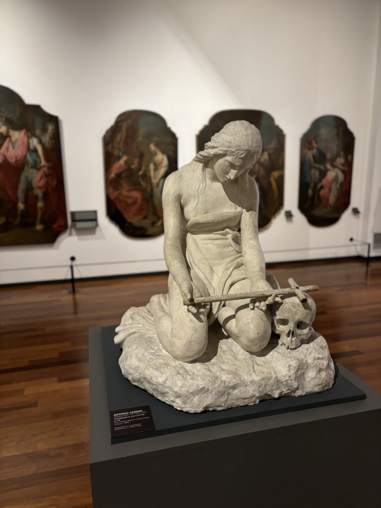 A statue of Antonio Canova with a skull and a cross.