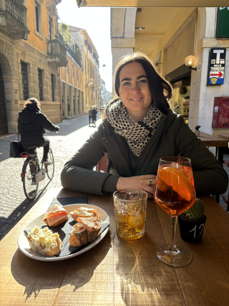 Claudia sitting at the Bacaro Frascolino with spunciotti and Spritz. Also a bike.