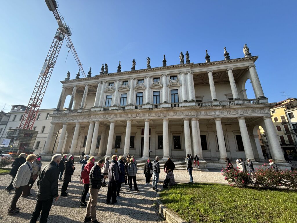 The front of Palazzo Chericati with a lot of people standing and a crane on the left.