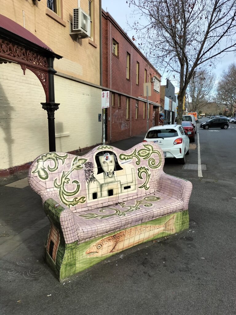 A bench in Fitzroy with some murales.