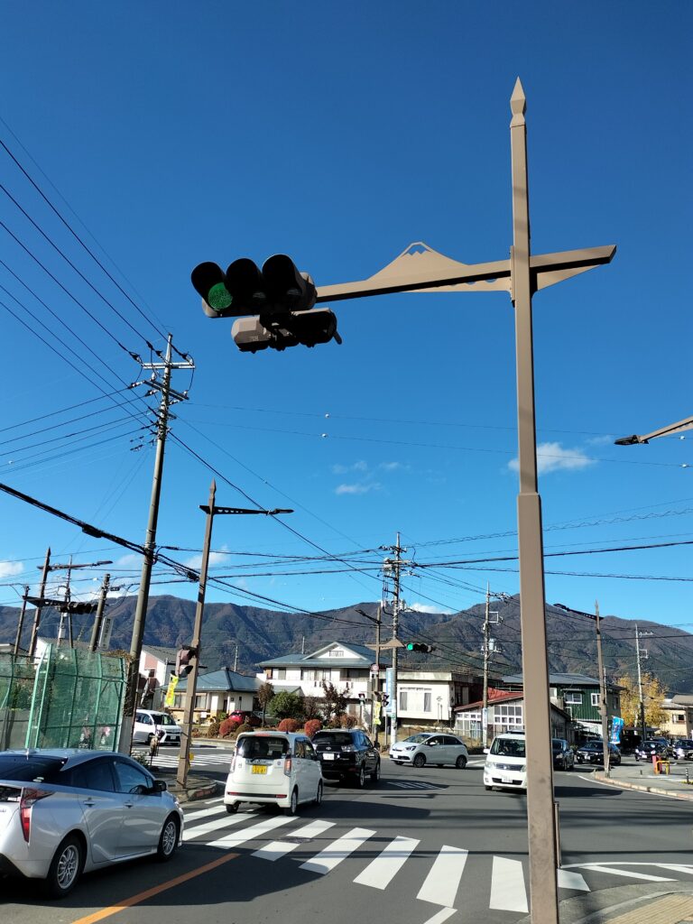 Traffic lights with Mt. Fuji design and some cars below.